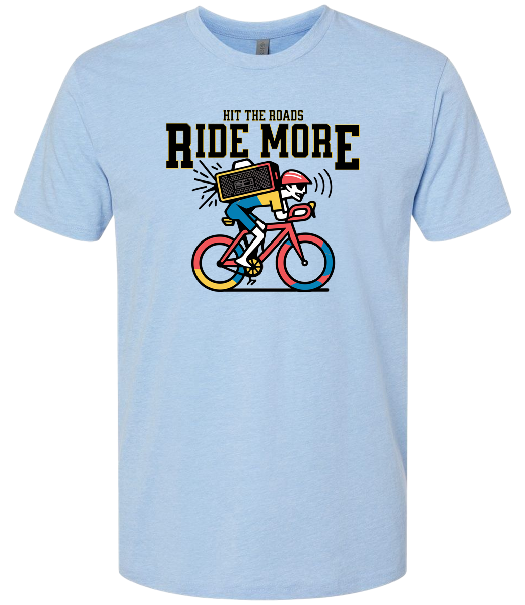 Light blue t-shirt with a graphic of a person on a bike and text 'Hit the roads, ride more' on a white background.